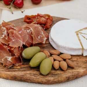 A delectable charcuterie board featuring brie cheese, prosciutto, olives, and almonds.