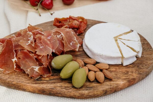 A delectable charcuterie board featuring brie cheese, prosciutto, olives, and almonds.